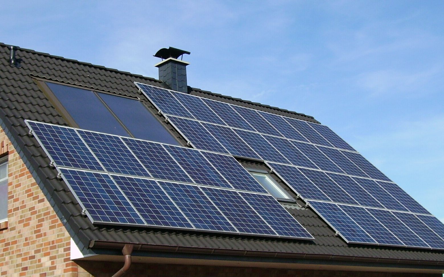 Residential rooftop solar installation on a tiled roof under a clear blue sky